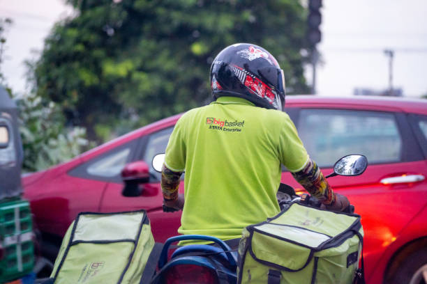 Rider delivery boy agent for Big Basket Tata Group in green uniform and helmet showing the last mile delivery for these digital startups stock photo
