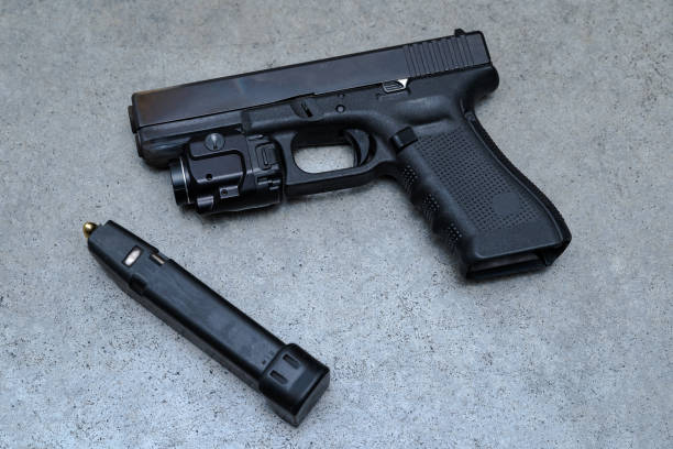 istock Pistol with a red dot sight and ammunition magazine on a gray desk 1763500247