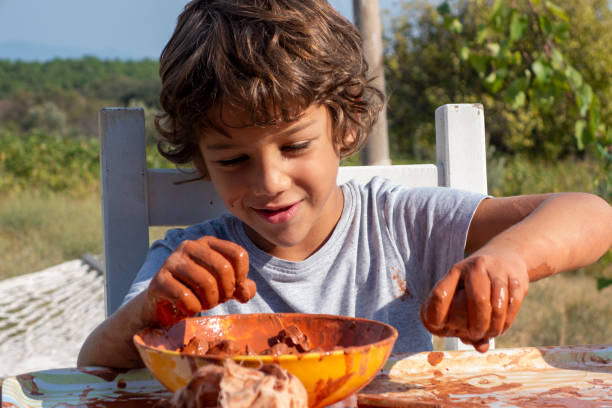 istock Boy playing with ceramic clay. He works for his creativity. A 9-year-old boy playing with ceramic clay in a bowl. He works at the table on the porch of the house. 1763508653