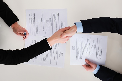 High Angle View Of Two Businesspeople Shaking Hand In Office