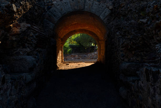 메리다 고대 로마 극장의 내부 입구와 출구 복도, 아치형 벽돌 천장과 화강암 돌이 터널을 통해 새벽 햇빛이 들어와 빛을 발합니다. - catacomb spooky europe flaming torch 뉴스 사진 이미지
