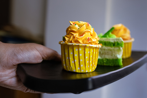Yellow and green cupcakes arranged on black platter