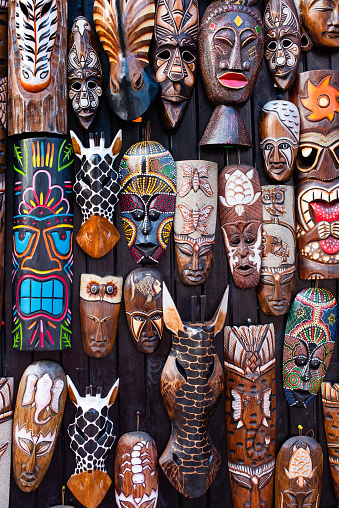 African traditional wood carved masks on the flea market. Handcrafted art background.