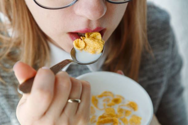 Closeup of mouth-eating corn flakes with milk on breakfast, unrecognizable woman. stock photo