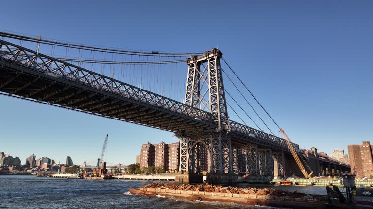 Aerial view of a barge passing under New York's Williamsburg Bridge