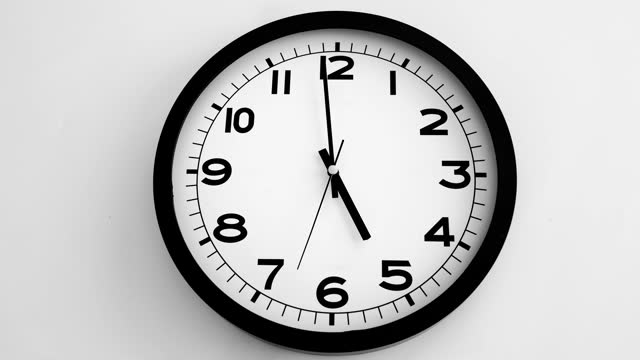 Closeup of White Clock Face on white wall clock, arrows show 17.00 or 05.00