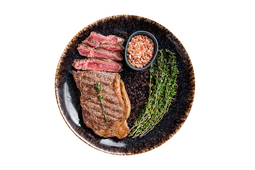 BBQ roast sliced New York  beef steak on a plate with thyme and salt.  Isolated on white background