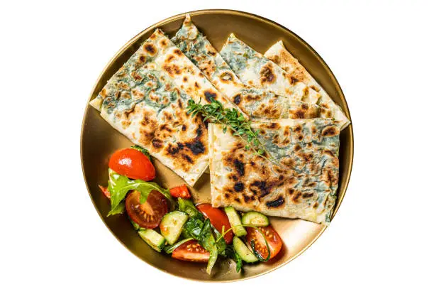 Gozleme flatbread with greens and vegetable salad on garnish.  Isolated on white background