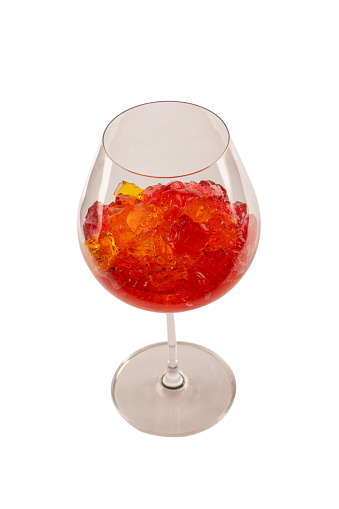 Sweet fruit jelly dessert in a glass isolated on a white background. Gelatin cubes.