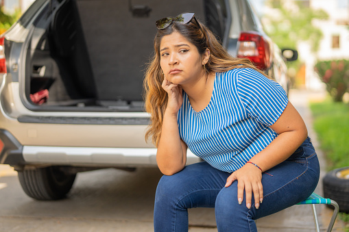 Woman sitting waiting for the tow truck to come and pick up her wrecked vehicle