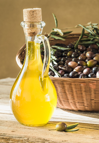 Fresh olive berries in basket and olive oil bottle background, harvest concept.