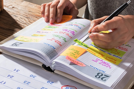 Close-up Of A Businesswoman Making Agenda On Personal Organizer At Workplace