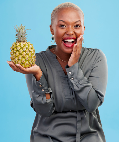 Portrait, wow and black woman pineapple in studio for detox, lose weight or diet nutrition on blue background. Fruit, face and African lady nutritionist show vegan, lifestyle or organic diet choice
