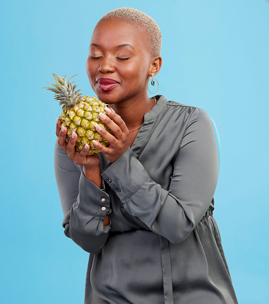 Pineapple, diet and black woman in studio with advice, lose weight or digestion and gut health tips on blue background. Fruit, detox or African nutritionist with organic, raw and superfoods guide