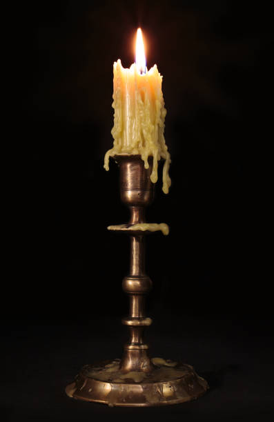 istock Old candle burn on a black background. Antique bronze candlestick 1763700764