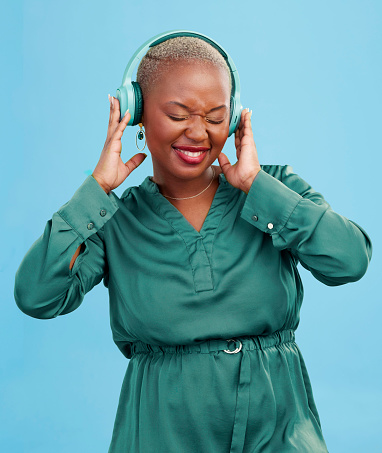 Happy black woman, headphones and dancing to music, audio track or sound against a studio background. African female person smile enjoying podcast, streaming or listening to entertainment on headset