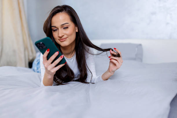 istock Young woman playing with her hair, while scrolling on her phone 1763773268