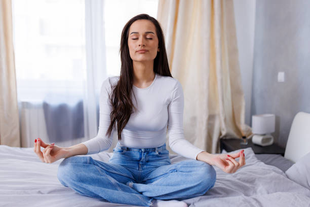 istock Young woman peacefully practicing yoga on her bed, while sitting in a lotus position 1763774227