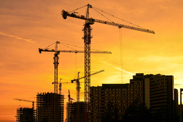 istock Tower cranes silhouette against yellow sunset 1763800100