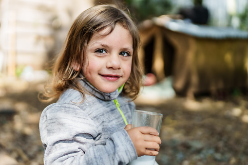 cheerful child having glass of milk outdoors