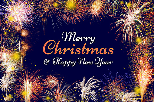 Merry Christmas and Happy New Year lettering on a night blue sky background with lots of beautiful fireworks as a frame.