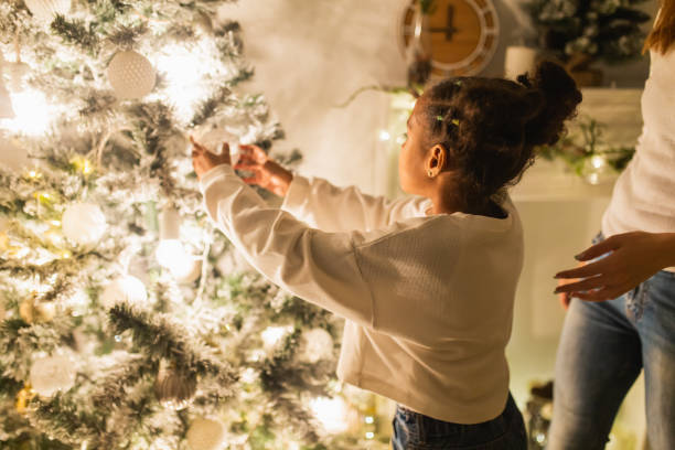 istock Girl with her mother decorate Christmas tree 1763851115