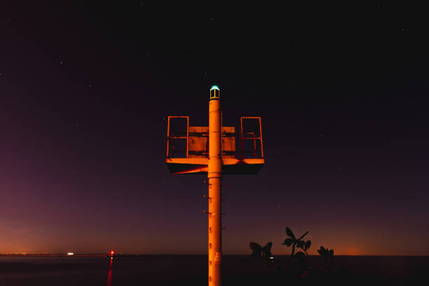 A long exposure landscape shot of a beacon on a starry night over Lake Erie.