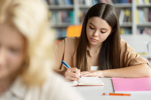 istock Pensive smart school girl taking notes, learning language in classroom. Back to school, education 1763926453