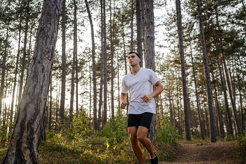 one man young caucasian male athlete running trough the woods in nature outdoor jogging in autumn or summer day sport fitness and recreation healthy lifestyle concept real people copy space