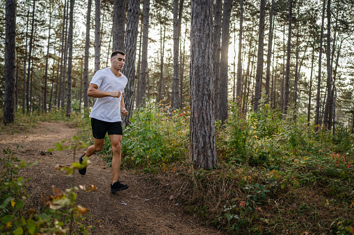 one man young caucasian male athlete running trough the woods in nature outdoor jogging in autumn or summer day sport fitness and recreation healthy lifestyle concept real people copy space