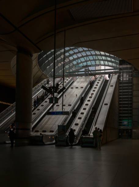 personas subiendo por las escaleras mecánicas dentro de la estación de metro de canary wharf. - people metal sign way out sign fotografías e imágenes de stock