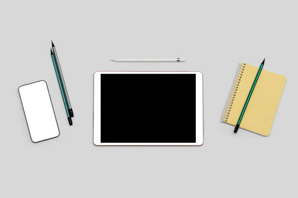 Tablet and phone with isolated screen, notepad, pencils lying on table. Mockup with white isolated screen. Education concept. Online Work and Distance Learning.