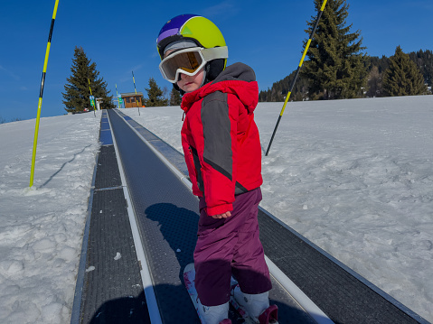 Lesson at skiing school: instructor teaching little skier how to make turns, young boy doing exercise on slope in children's area