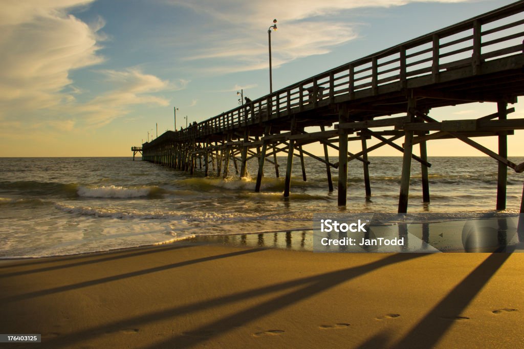 Beach Pier over the Ocean Late Afternoon Fishing Pier at Oak Island beach, North Carolina, late afternoon.   Beach Stock Photo
