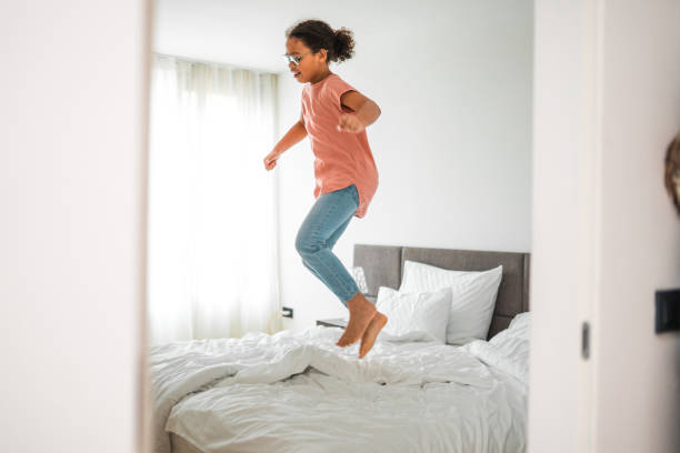 istock Happy Funny Child Girl Jumping On Bed Alone Feeling Joy 1764036713