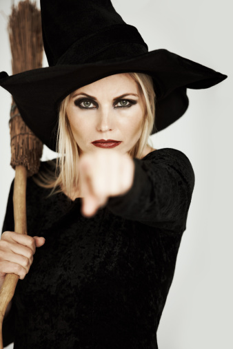 close-up of a white-haired witch with her broom against an abstract background