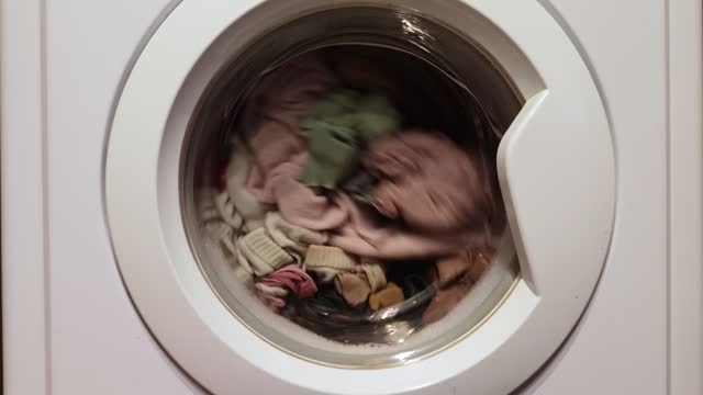 Modern automatic washing machine loaded with colorful clothes washing home laundry washes dirty clothing.