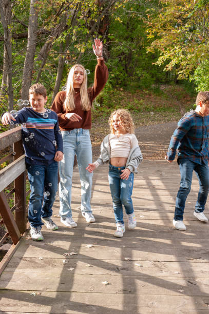 istock Blending Families: four kids chase bubbles on a quaint bridge during the fall season. 1764130943