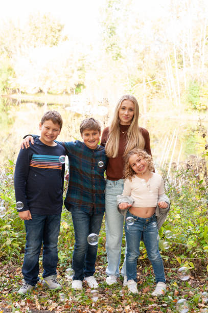 istock Blending Families: four kids pose near lake/woods with bubbles in front of them. 1764130964