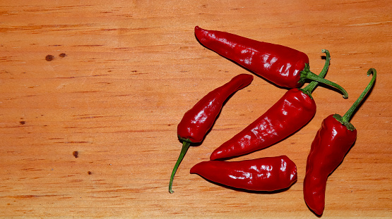 Top view of chilli peppers isolated on the brown textured wood background