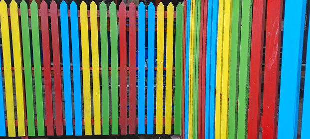 Multi colored rainbow wooden fence in garden background