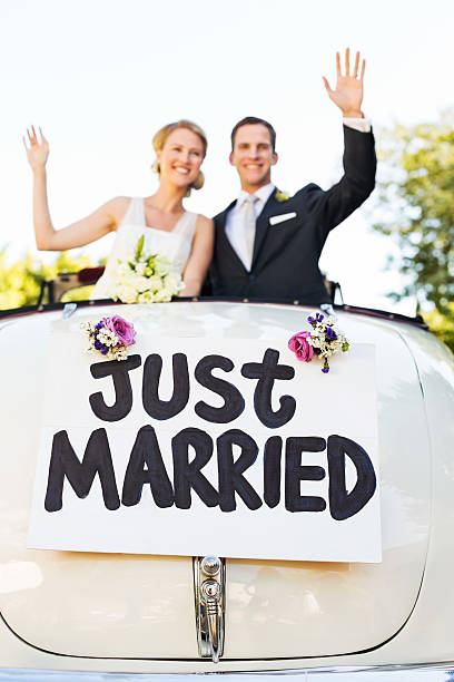 couple heureux dans une voiture décapotable agitant - traditional ceremony sign symbol wedding photos et images de collection