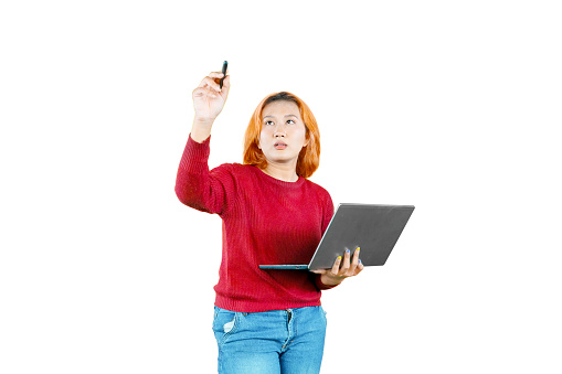 Young Asian female designer or entrepreneur writing or drawing on screen with stylus pen while holding a laptop computer isolated on white background