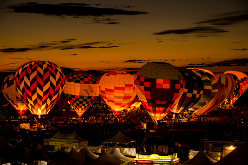 ground level view of hot air balloons glowing at night from flame torch