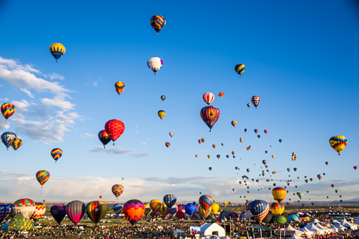 This is a photograph taken at sunrise of five hot air balloons in Temecula California. The balloons have  a variety of beautiful bright colors.