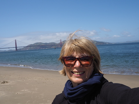 Selfie tanken happy Woman 50+in San Francisco in Front of Golden Gate Bridge