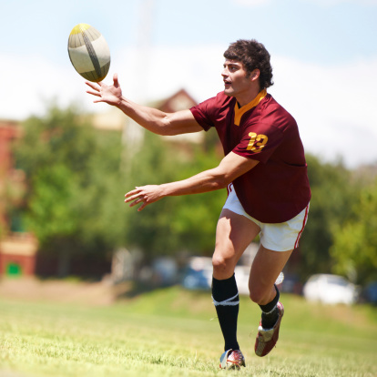 A rugby player throwing a ball in the air