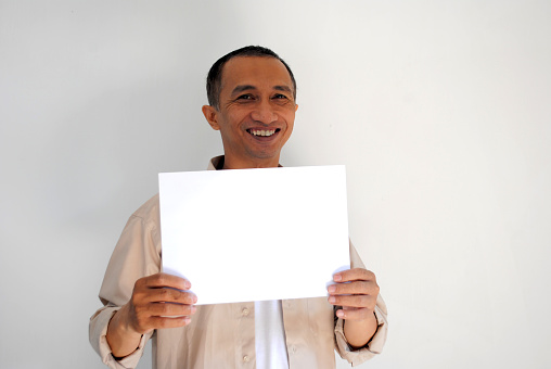 Smiling Asian man is holding an empty white paper.