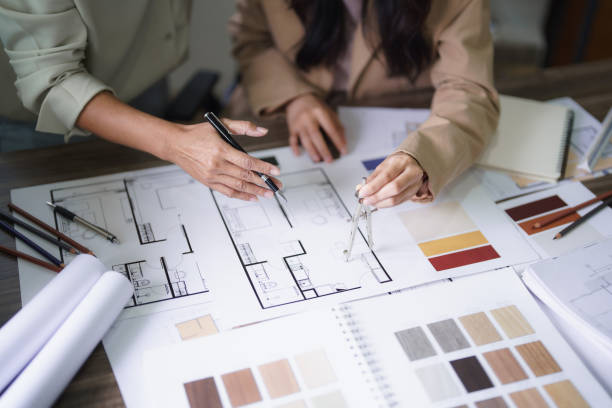 istock Two female architects discuss interior design building project and use divider compass on blueprint 1764271943