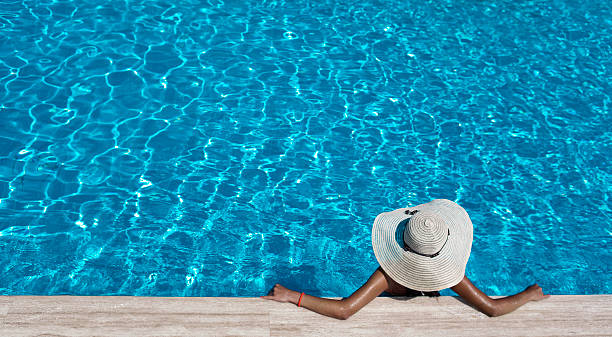 Woman with hat relaxing by the pool stock photo